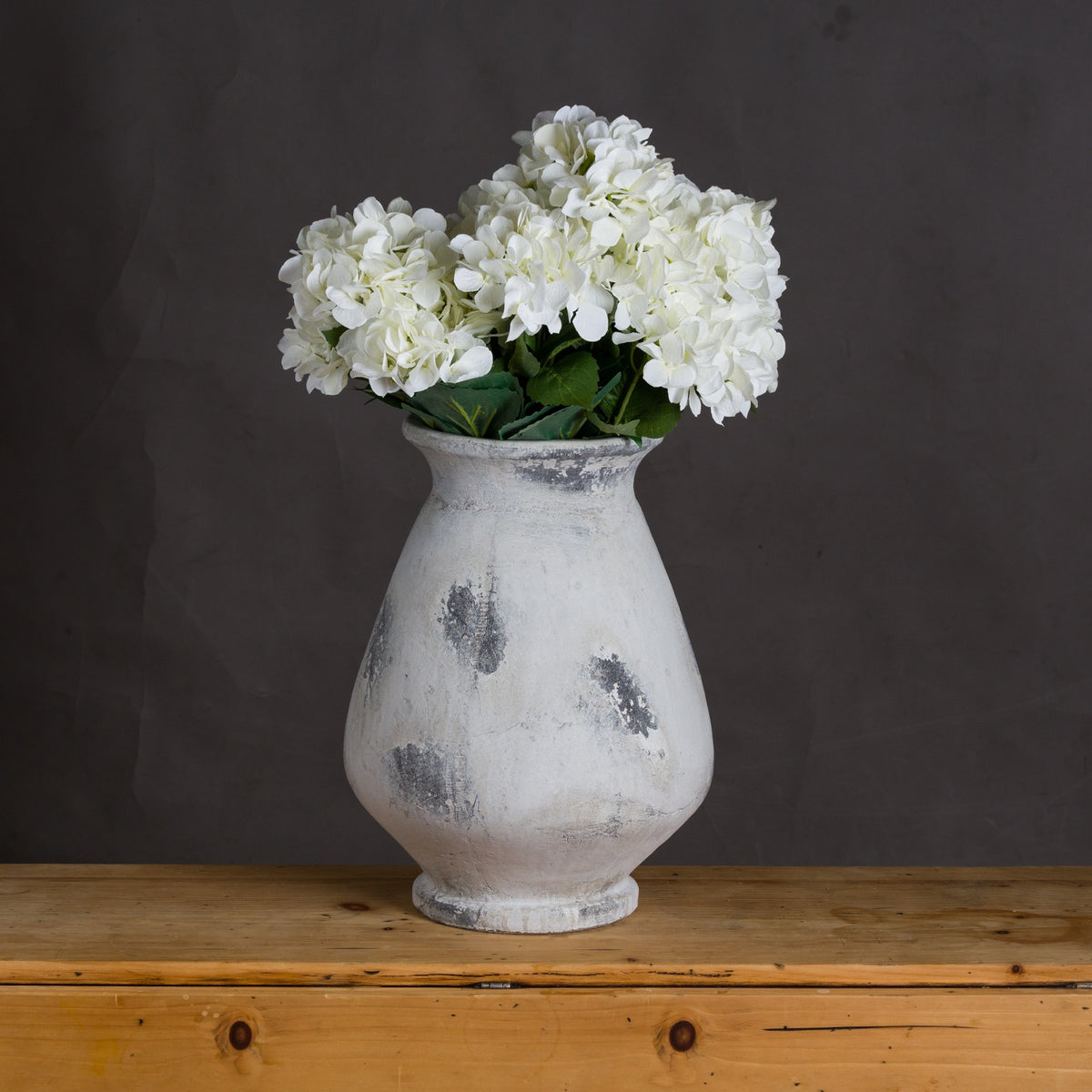 Naxos Large Antique White Vase styled with white flowers on a wooden surface