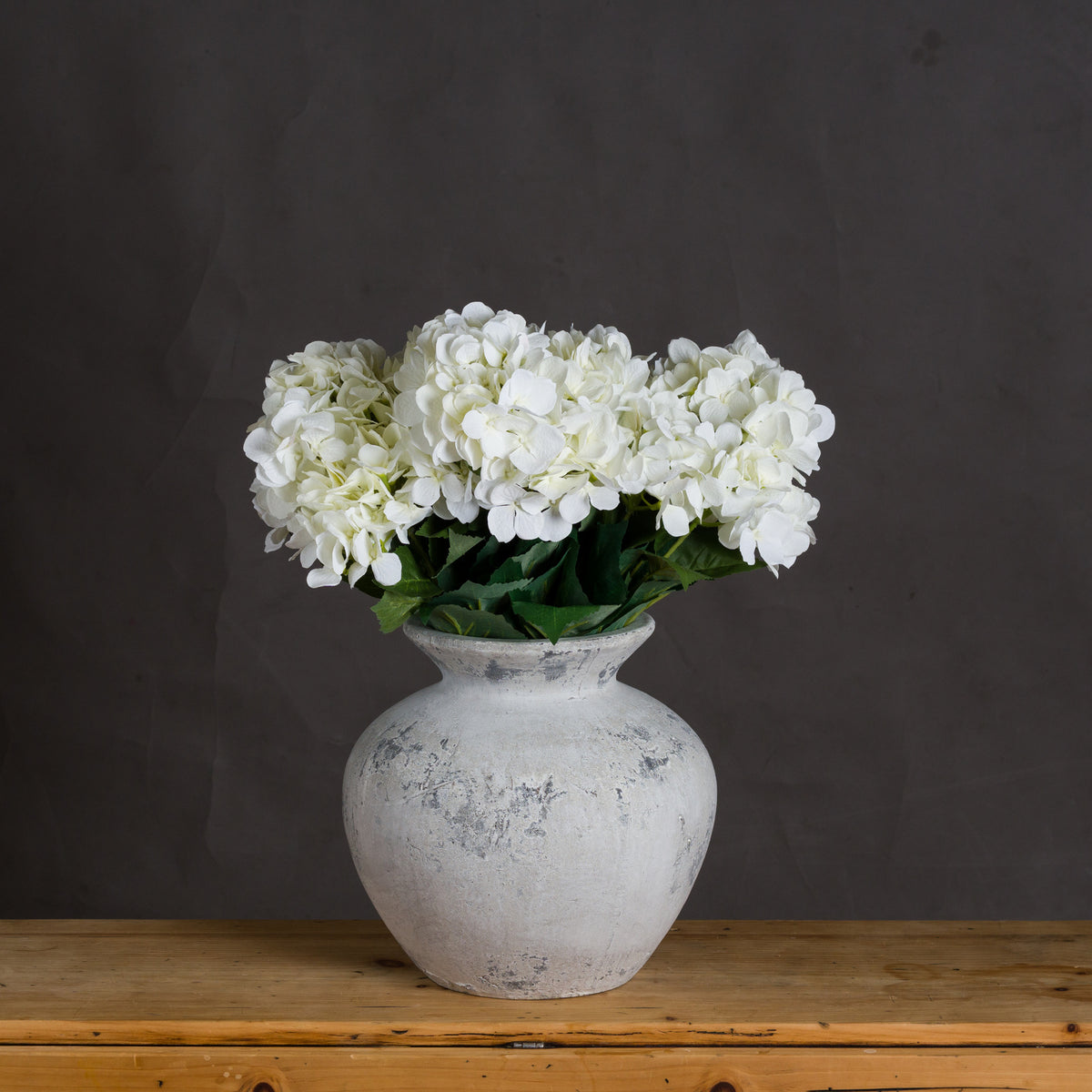 Darcy Antique White Vase holding white hydrangea-style blooms on a wooden surface