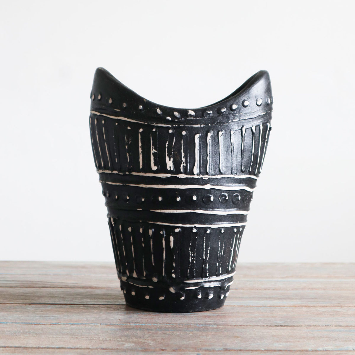 Dark Swirls Shaped Vase displayed on a wooden surface with its curved rim visible