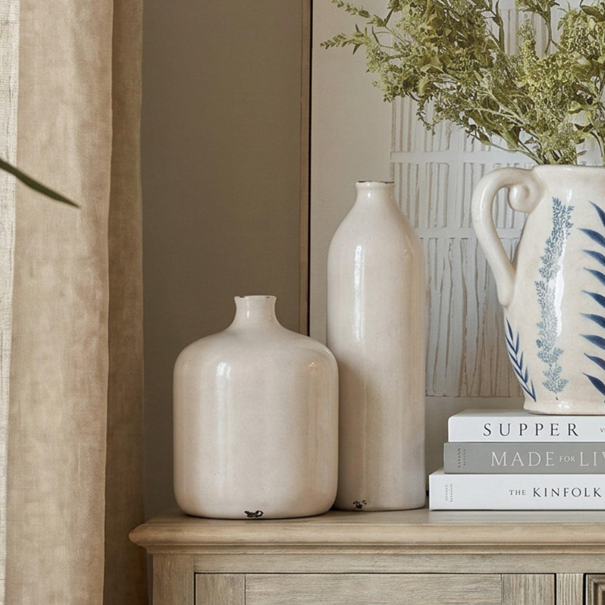 Tall cream Garda Glazed Gisela Vase at rear beside a shorter vase and a patterned jug on a cabinet