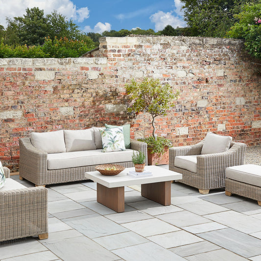 Capri Collection outdoor rattan armchair with cream cushions, weather-resistant wicker garden lounge chair styled on stone patio