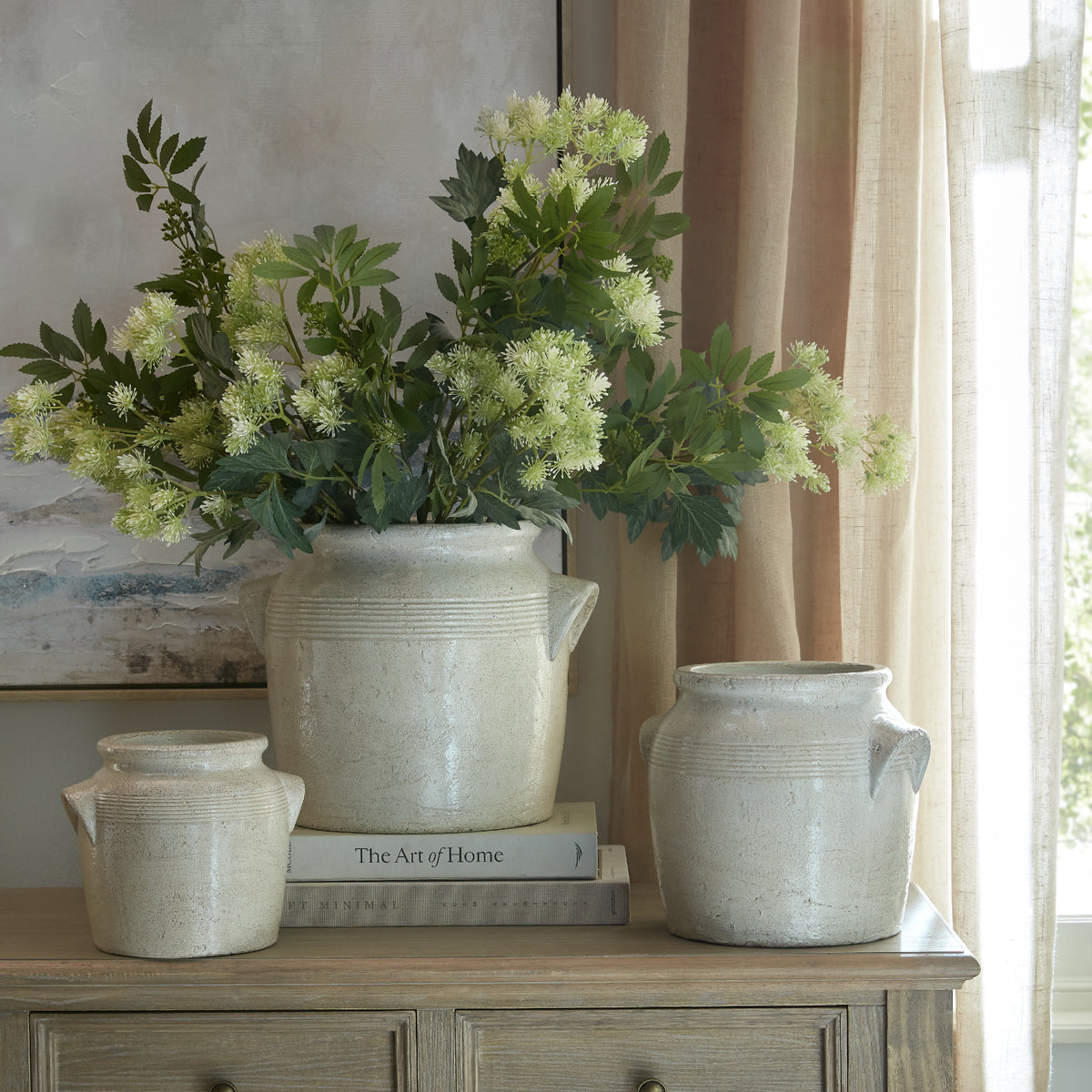 Tarn large handled pot at the centre of a three-pot display, styled with flowers beside a window