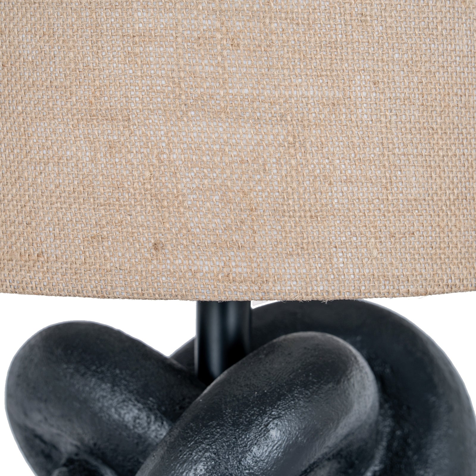 Close-up of a lamp with a beige fabric shade and black metal base.