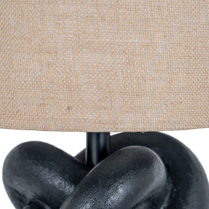 Close-up of a lamp with a beige fabric shade and black metal base.
