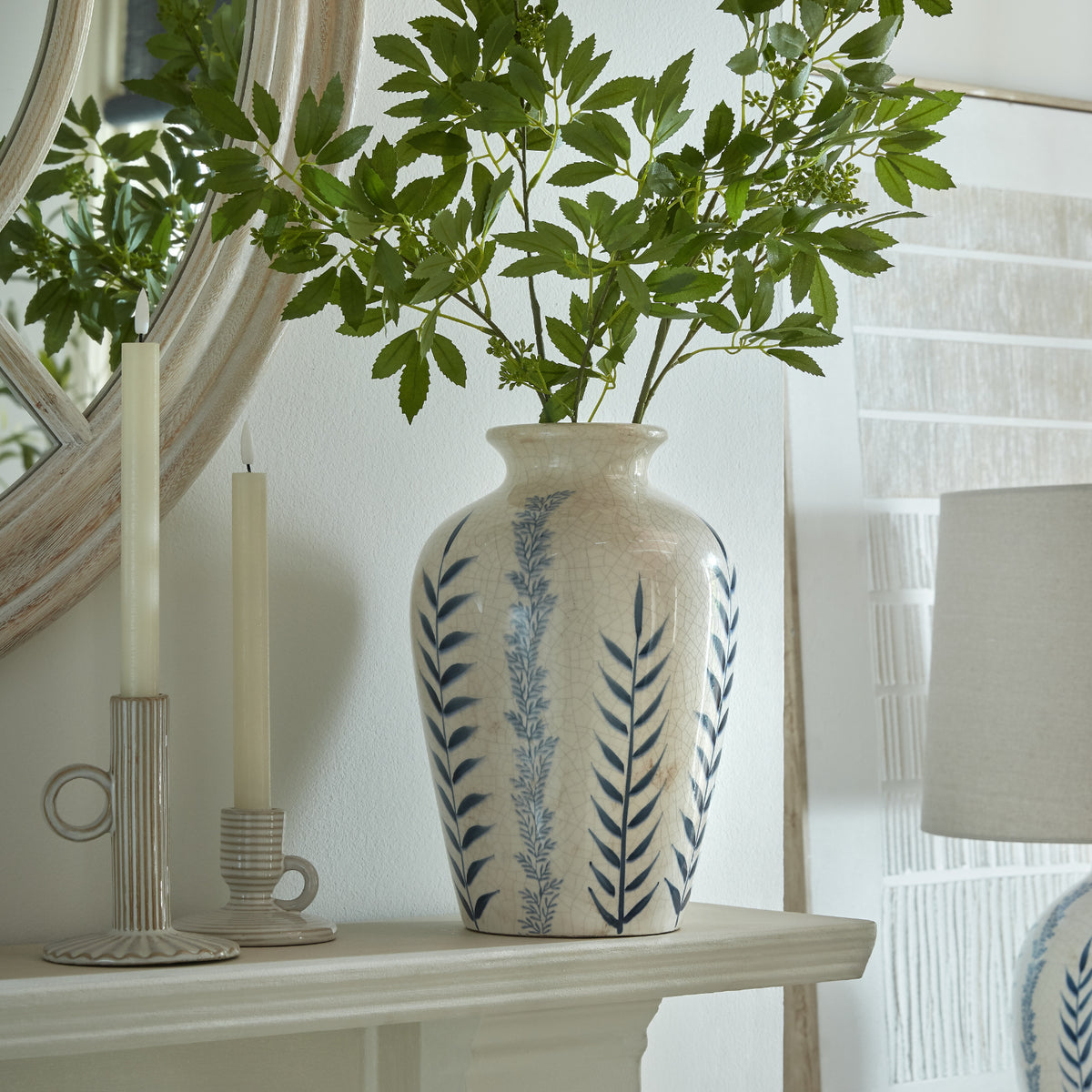 Classic Blue Flora Juniper Vase with foliage on a console beside a mirror