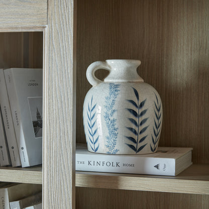 Blue Flora Amphora Jug Vase displayed on a book in a wooden shelving unit